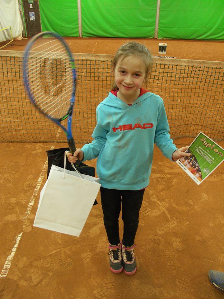 młoda zawodniczka prezentuje sprzęt tenisowy i nagrody po turnieju