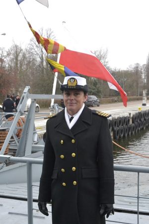 Kpt. Marynarki Wojennej Katarzyna Mazurek stoi na tle biało czerwonej bandery